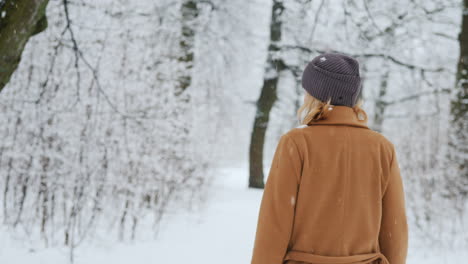 una mujer con un cálido abrigo clásico camina por el bosque de invierno