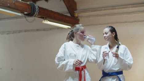 front view of martial artists drinking water and talking in gym