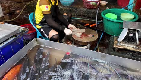 person cleaning fish at a busy market stall