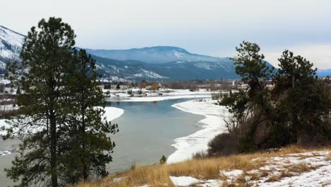 tracking shot of the thompson river surrounded by farmland in the winter month