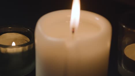 Close-Up-Of-Candles-Burning-On-Table-In-Dark-Room