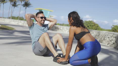 chica ayudando a hombre con ejercicios abdominales