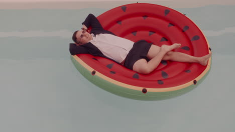 man relaxing on watermelon pool float