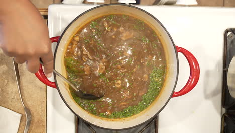 cubriendo el arroz salvaje y la sopa de champiñones con cebolletas frescas y revolviéndolos en la olla en la estufa - vista superior de la serie de arroz salvaje