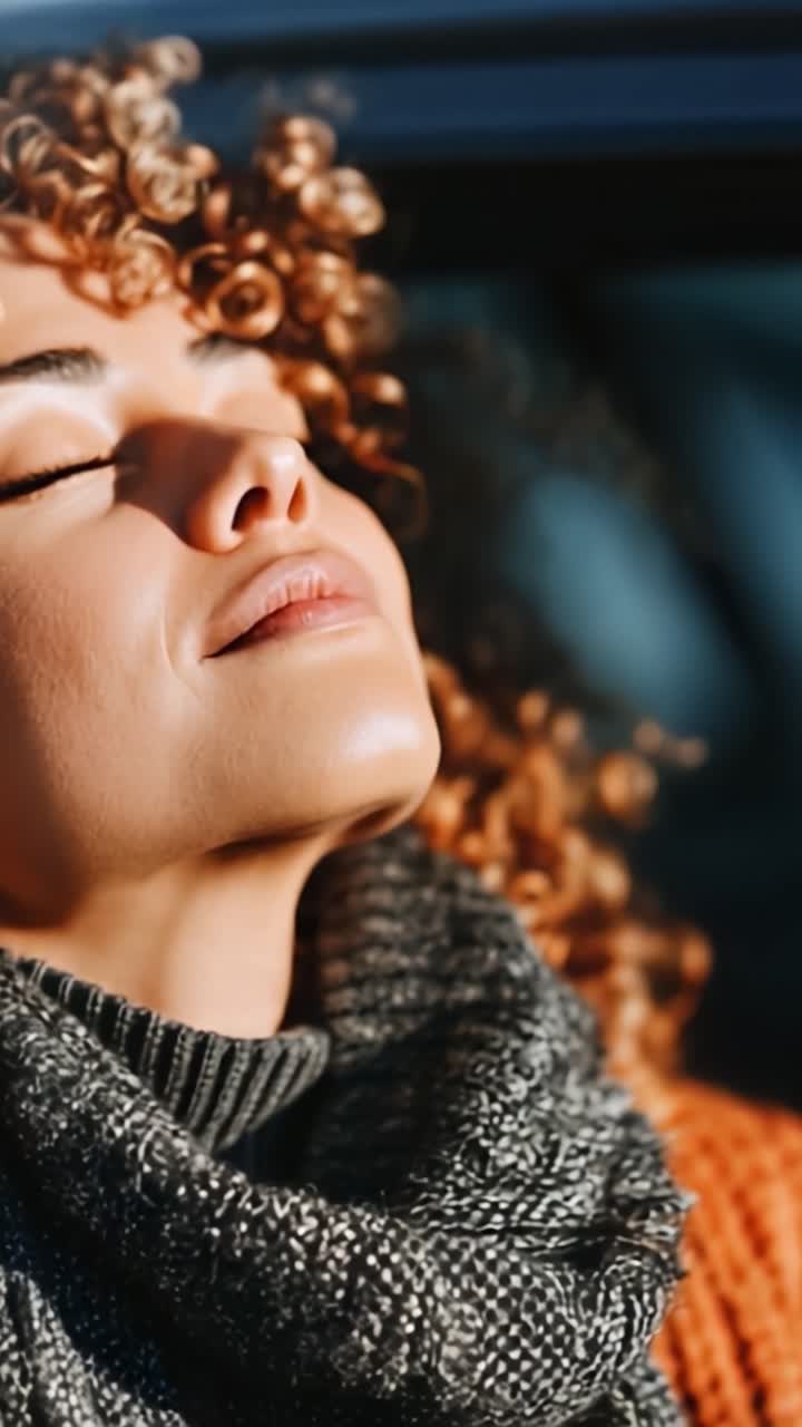 Catturare un Momento di Serenità: Una Donna con Bellissimi Capelli Ricci si Gode il Caldo Sole con gli Occhi Chiusi, Abbracciando Pace e Calma nella Natura.