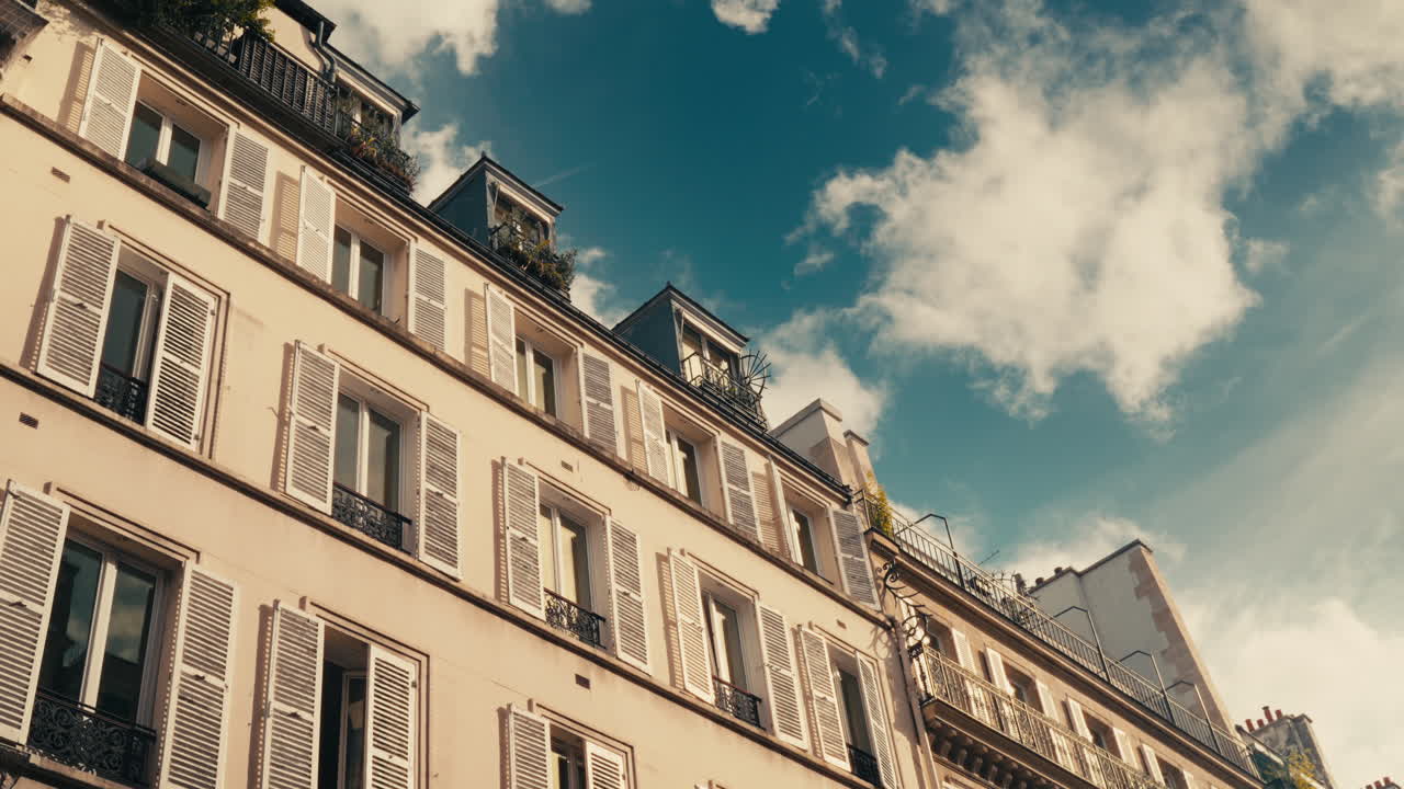 Parisian Building Facade with White Shutters and Cloudy Sky
