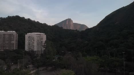 acercamiento aéreo al amanecer y panorámica mostrando la montaña corcovado en río de janeiro detrás de una cadena montañosa desde otra parte de la ciudad, revelando la ciudad debajo