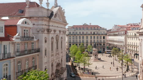 Traditional-narrow-city-streets-with-beautiful-architecture-surrounding-city-square-and-pedestrians-walking-around-city-center-in-Lisbon,-Portugal