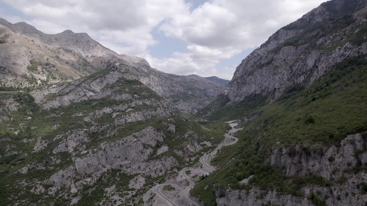 video de drones del avión frontal avanzando en la autopista sh20 en albania, a la altura de javor y mreg, camino de serpientes, se pueden ver pequeñas casas de la ciudad, cielo nublado