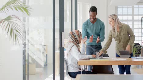 happy diverse business people discussing work at table with laptop in slow motion