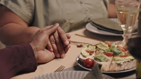 couple holding hands at dinner table