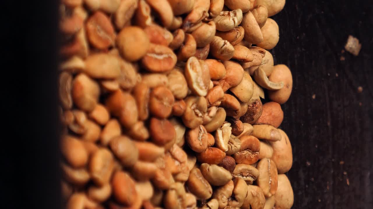 Vertical Close up slow motion shot of roasted coffee beans kopi luwak while the beans are stirred and roasted in a wok with a wooden spoon in Bali, indonesia