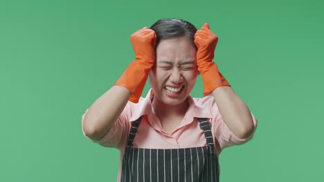 그린 스크린 스튜디오에 서 있을 때 머리가 아프고 왜 그런지 모르는 아시안 여성 집사.