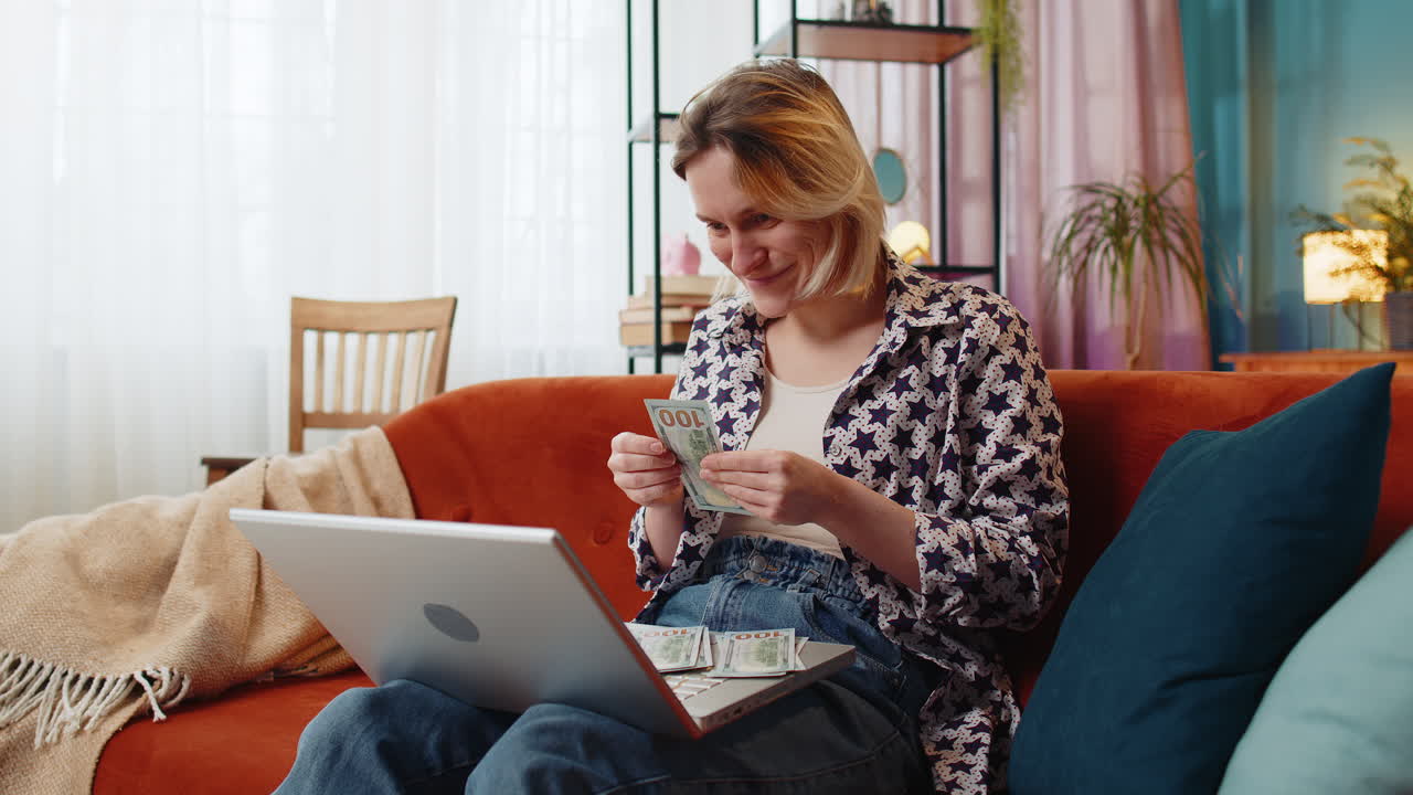 Rich happy young woman freelancer counting money cash use laptop computer calculate domestic bills