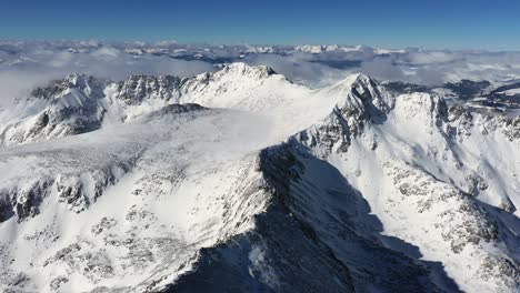 aerial view, breathtaking winter landscape, snow capped mountain peaks on sunny day, drone shot