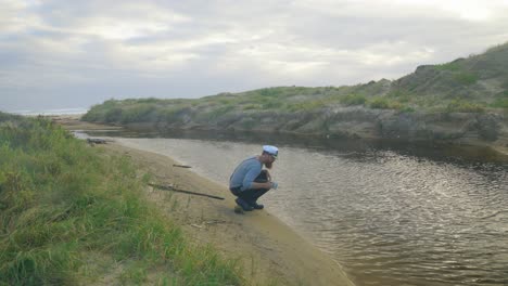 A-1900s-sailor-collects-water-from-a-stream-while-stranded-on-the-coastline