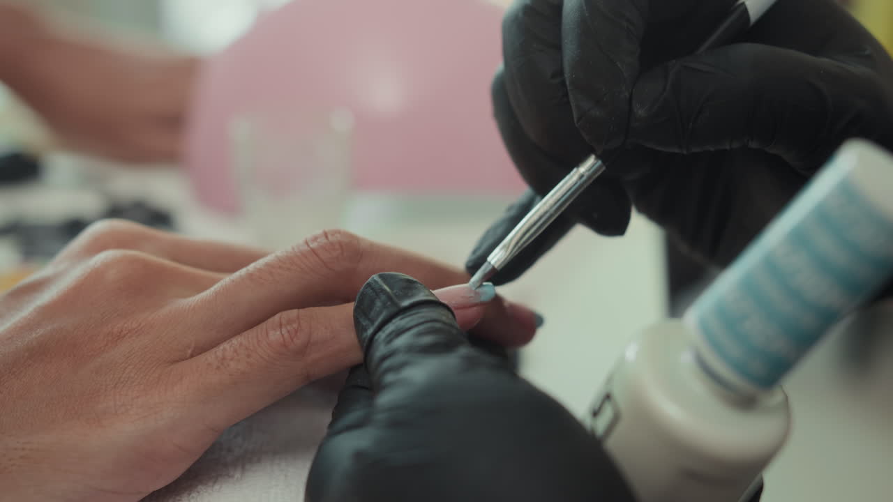 Expert Applying Gel Polish on Nails of Woman at Salon