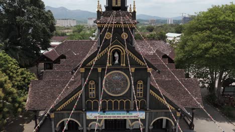 ascending drone footage in front of an unique wooden church, the black cathedral of kon tum city, 100 years old, vietnam