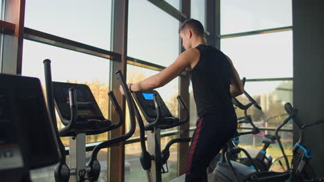 Un-Hombre-De-Fitness-Retrato-Se-Calienta-Antes-De-Entrenar-En-Una-Bicicleta-Elíptica-En-El-Gimnasio.-Ejercicio-Cardiovascular-De-Entrenamiento-Masculino-De-Primer-Plano-En-Bicicleta-Cruzada-En-Fitness