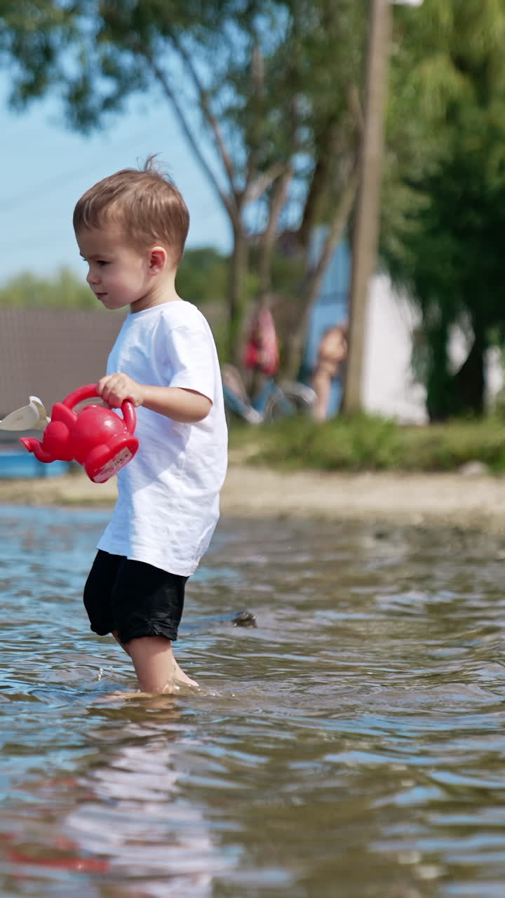 Boy playing on the beach with water. Small kid having fun at river sand beach. Vertical video