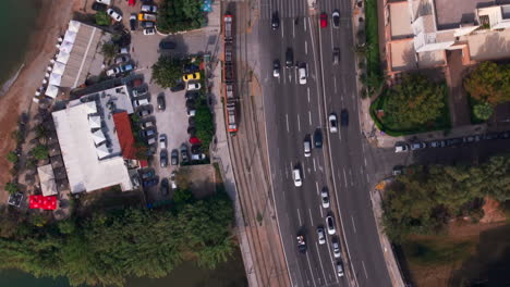 disparo aéreo de arriba hacia abajo de un tranvía conduciendo a lo largo de un lado de una carretera ocupada