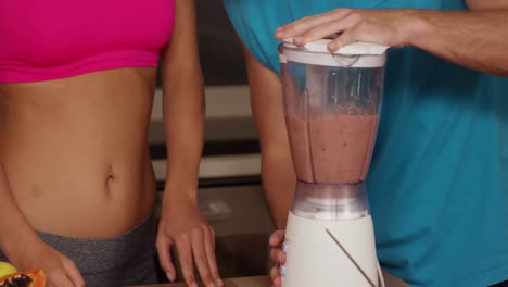 Midsection-of-a-couple-preparing-a-smoothie