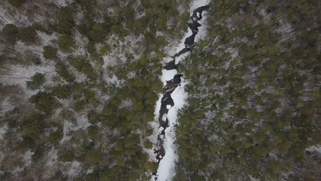 drone flying high above snowy mountain river in winter