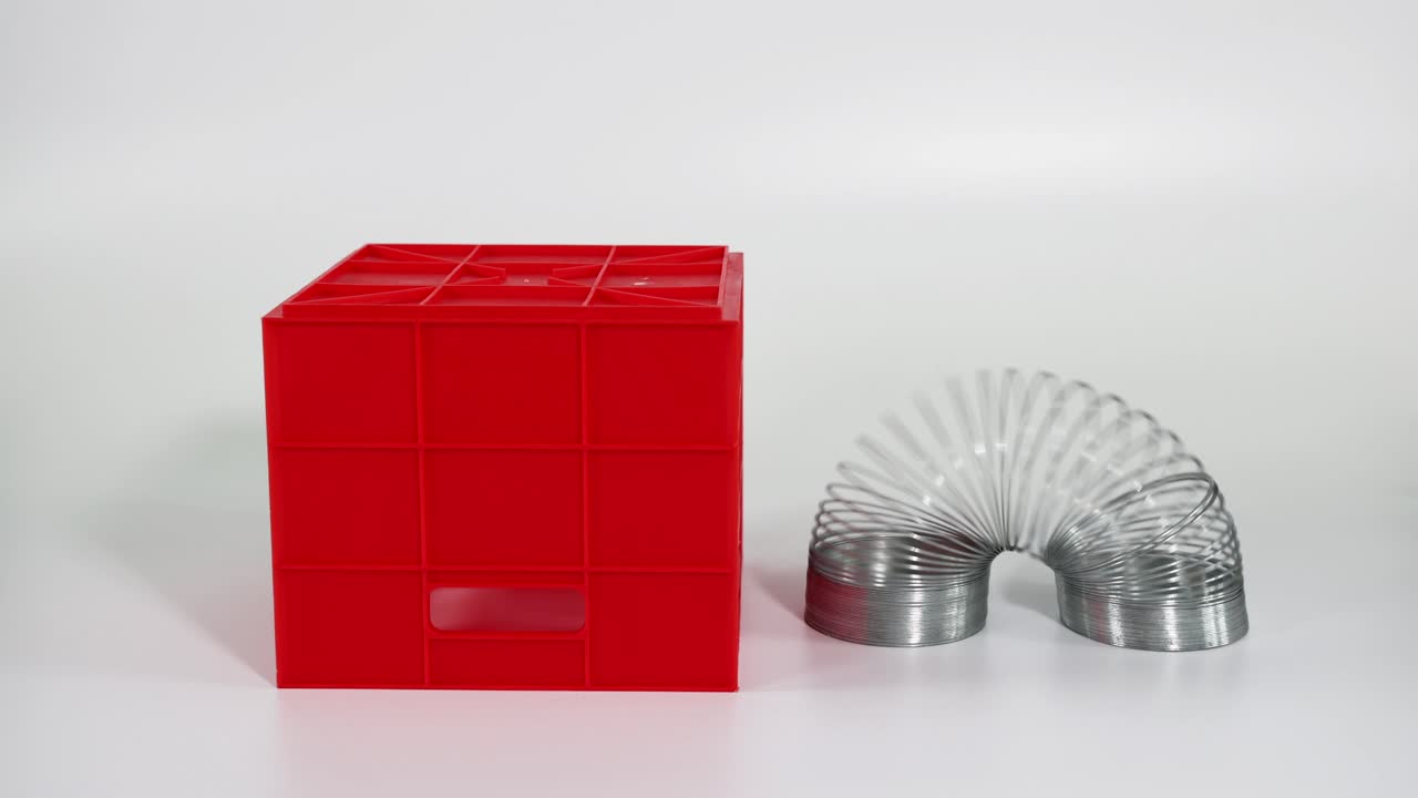 손은 빨간 블록 계단 위에 슬링키 장난감을 조작합니다.