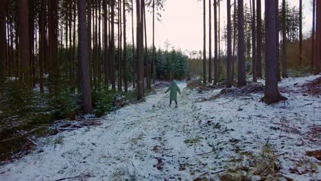 a young girl enjoying the winter season in a warm jacket is spinning in the middle of the forest