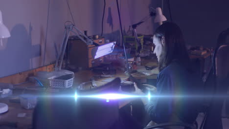 animation of glowing light over caucasian woman working in workshop