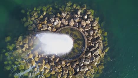 Aerial-view-over-the-Ocean-Fountain-with-a-green-ocean-in-background-and-some-rocks,-in-Paço-de-Arcos,-PDA,-Oeiras,-Lisbon,-Portugal