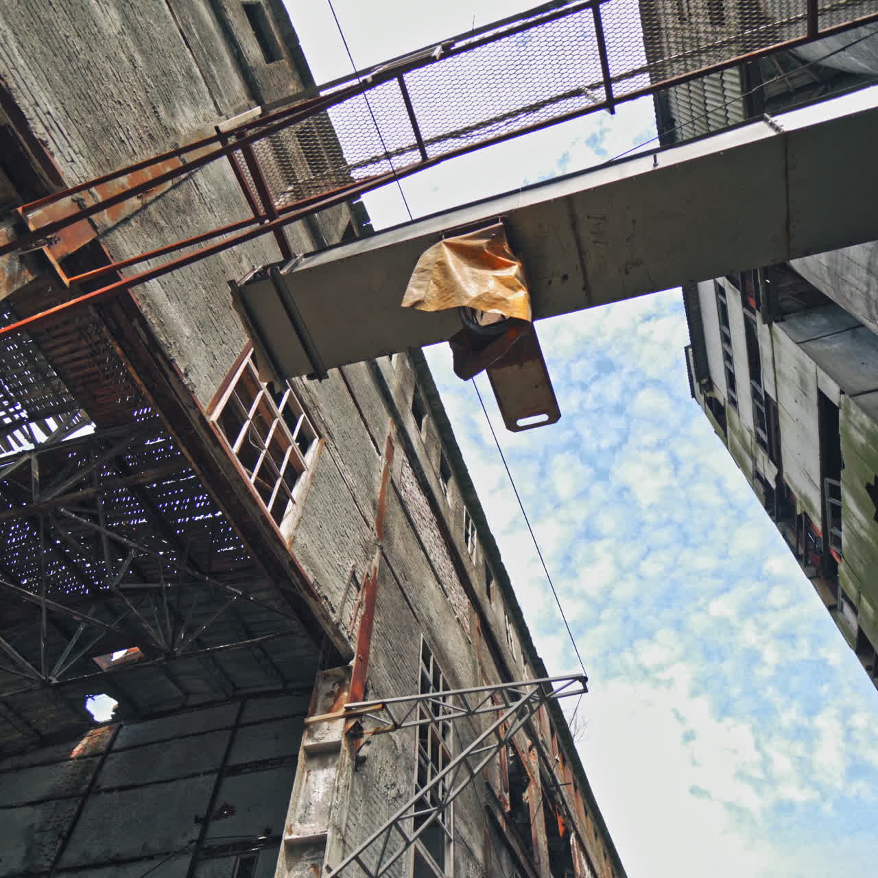 The ruins of an old factory. The abandoned building was covered with grass and trees. Holes and cracked in the walls and ceiling. Reinforced concrete and brick construction collapse.
