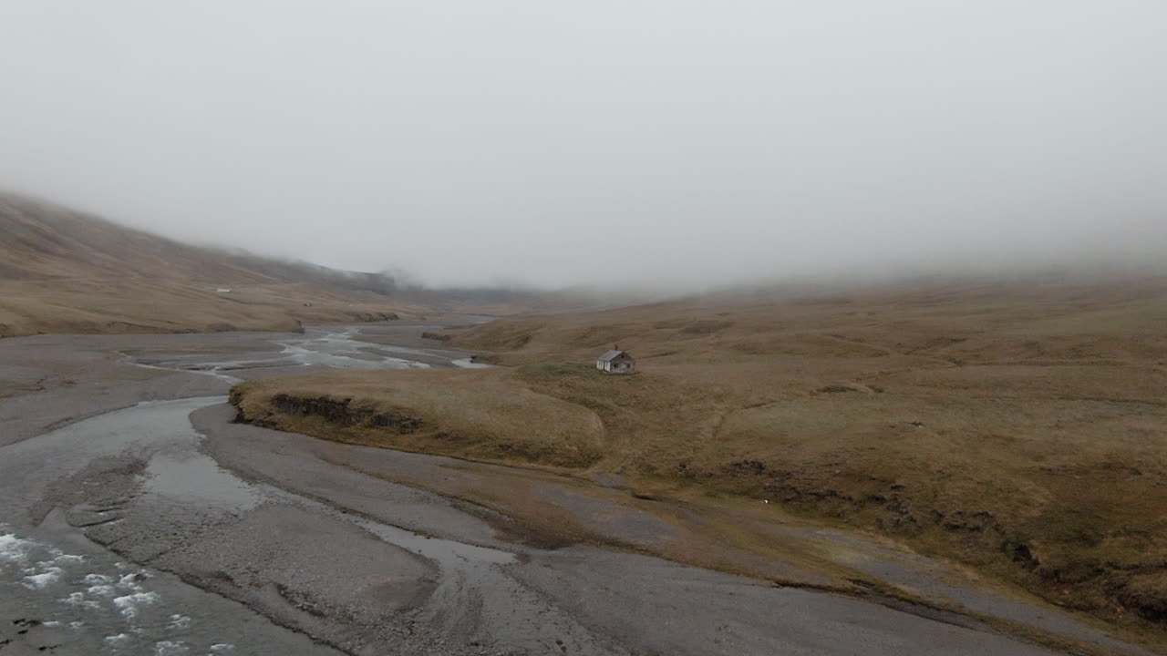 Foggy river scenery and abandoned house not far from shore, Iceland