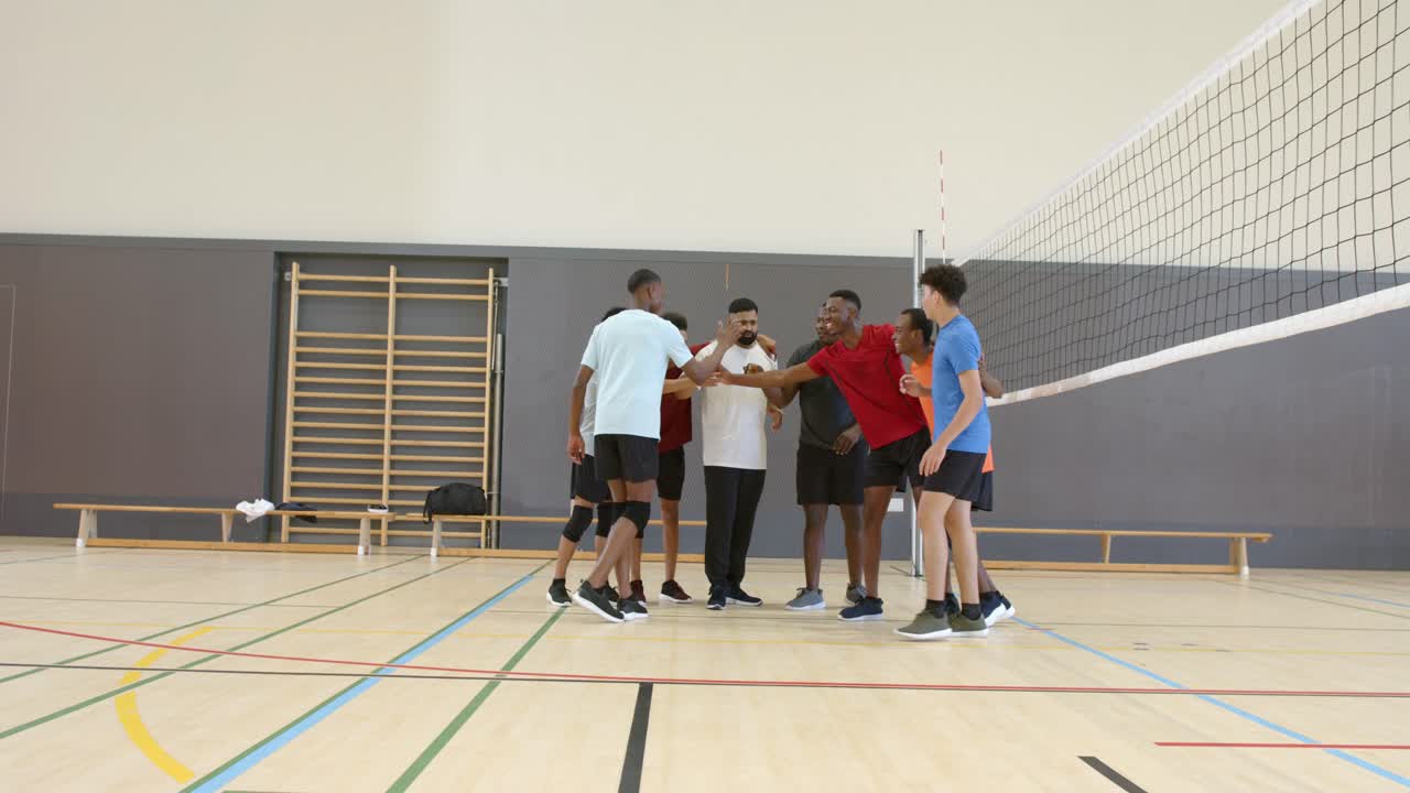 Male volleyball teammates stacking hands at net, fist-bumping, listening to leader guiding spots