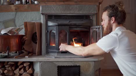 man closing the glass door of the traditional heating stove