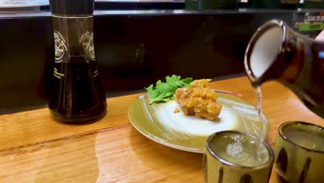 sake being poured beside chicken karaage dish