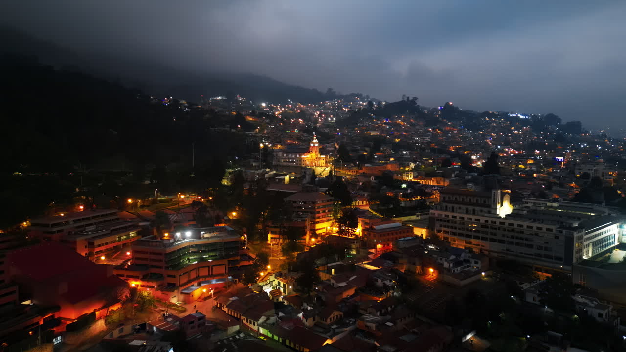 Aerial drone view of skyscrapers lighting up the skyline against the Andean foothills in Bogota, Colombia in the evening