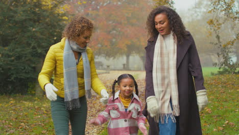 smiling multi-generation female family walking through autumn countryside together