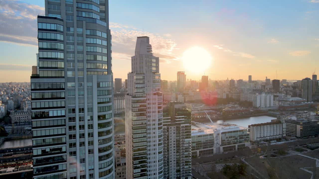 Imagens aéreas de drone 4K voando por apartamentos de construção moderna revelando a vista da cidade durante o pôr do sol em Puerto Madero, Buenos Aires, Argentina