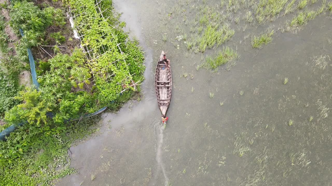 vista aérea de un aldeano empujando un bote sobre arrozales inundados en las zonas rurales de bangladesh-1