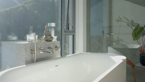 a serene bathroom with a white bathtub is bathed in natural light from a large window