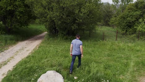 seguimiento a través de drone de un turista caminando en los bosques de la agujera de chisinau, pasando por un punto de referencia de roca en un pueblo de bulgaria