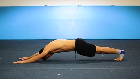 a guy doing a static hold in a gymnastics gym working out his abs and core muscles still shot