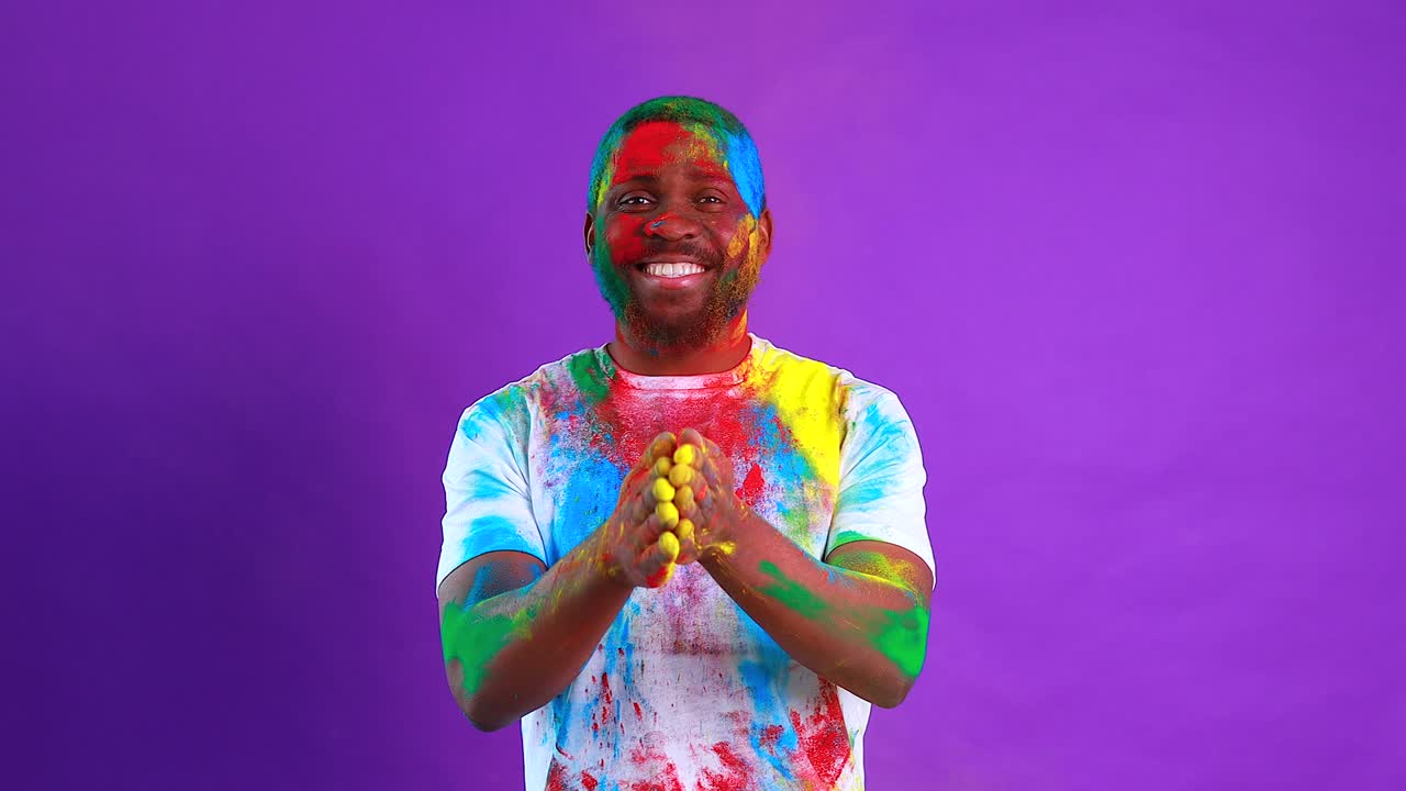 L'uomo afroamericano celebra il festival di holi sullo sfondo viola dello studio