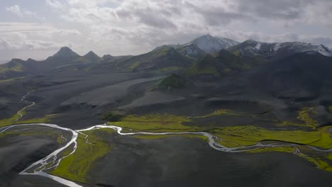 un video de drones de las tierras altas del sur de islandia que muestra arenas negras, musgo verde y nieve en las montañas
