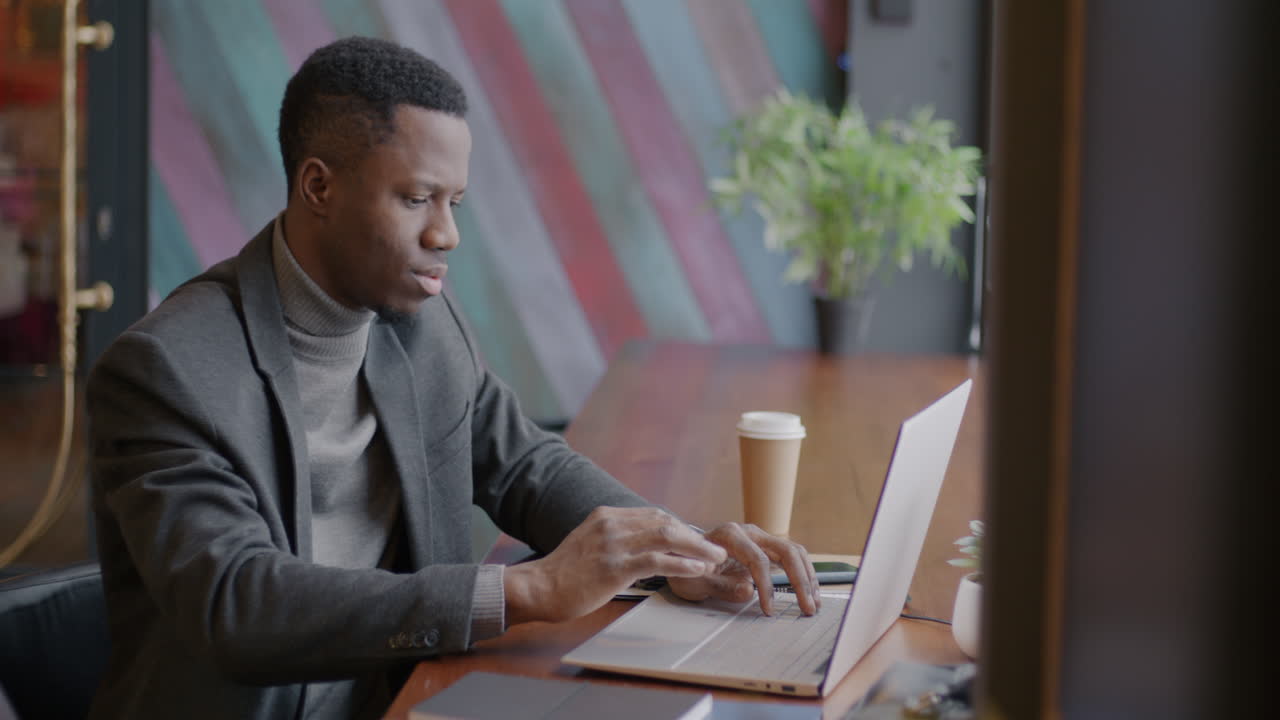 Man Working on Laptop in a Coffee Shop