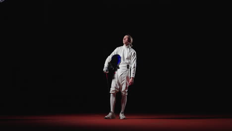 young male fencer in white suit with sword and mask posing