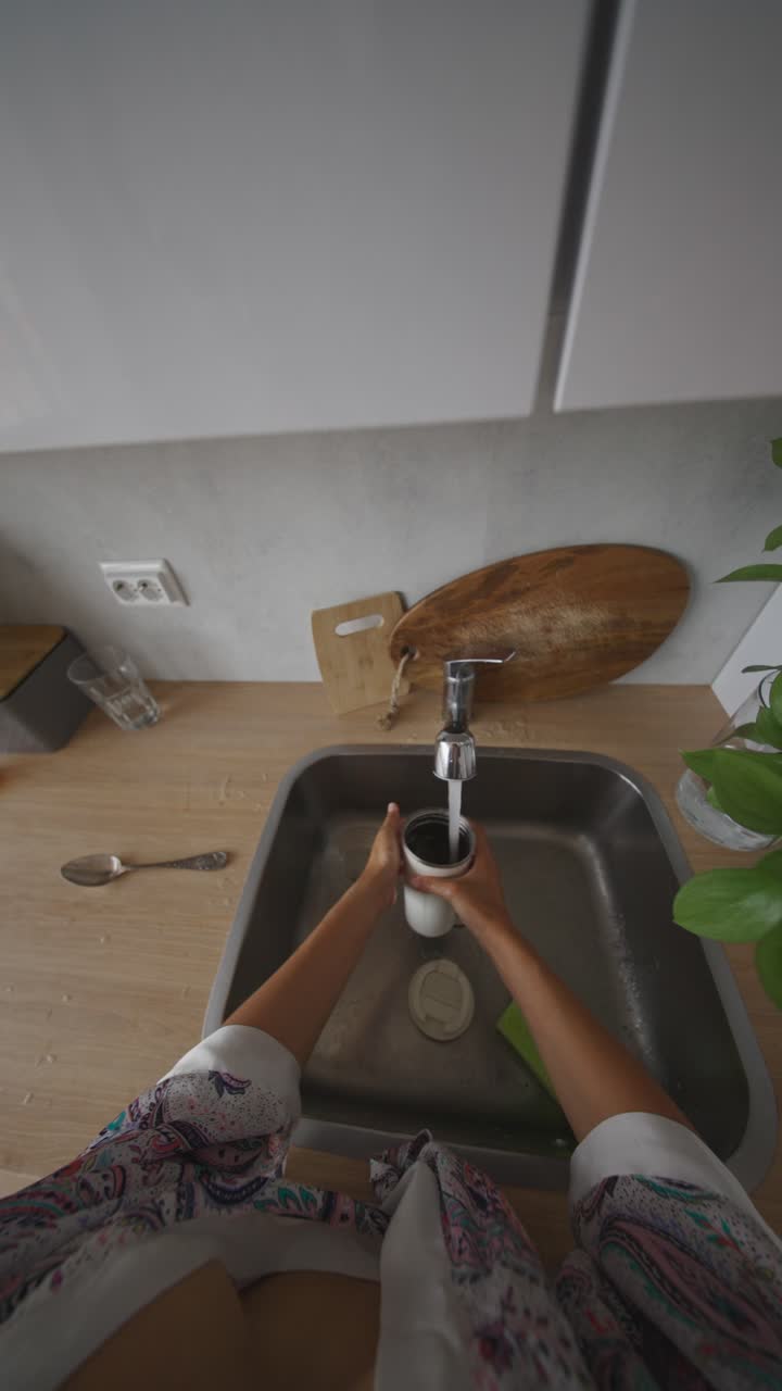 Lavando una taza y una botella en el fregadero de la cocina
