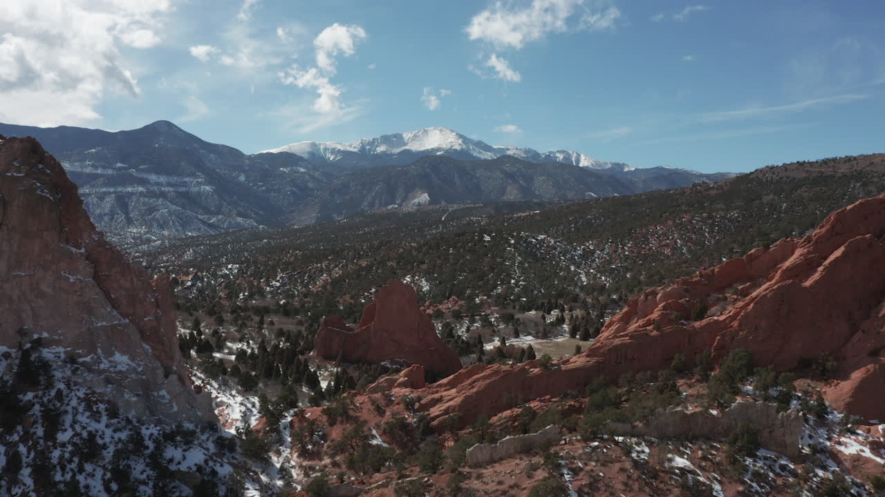 Aerial pan up reveal shot of Pikes Peak with red rocks in foreground