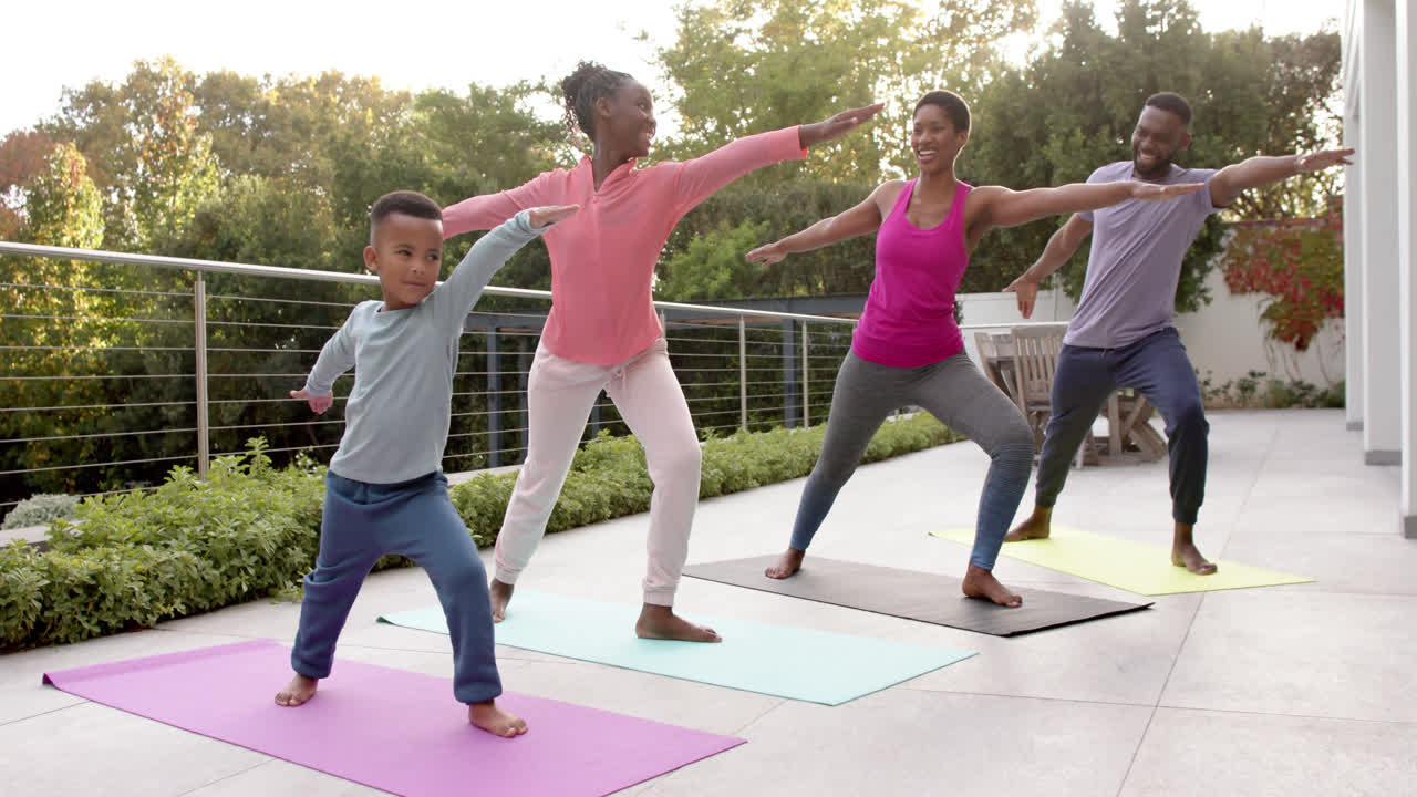 felices padres afroamericanos, hijo e hija practicando yoga en un jardín soleado, en cámara lenta.